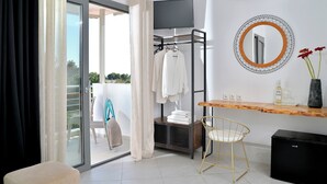 Un baño moderno con una puerta de vidrio que da a un balcón, un perchero, un tocador de madera con un espejo y un mueble de almacenamiento negro.