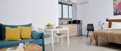 A modern living room with a sofa, coffee table, and a dining area with a table and chairs.