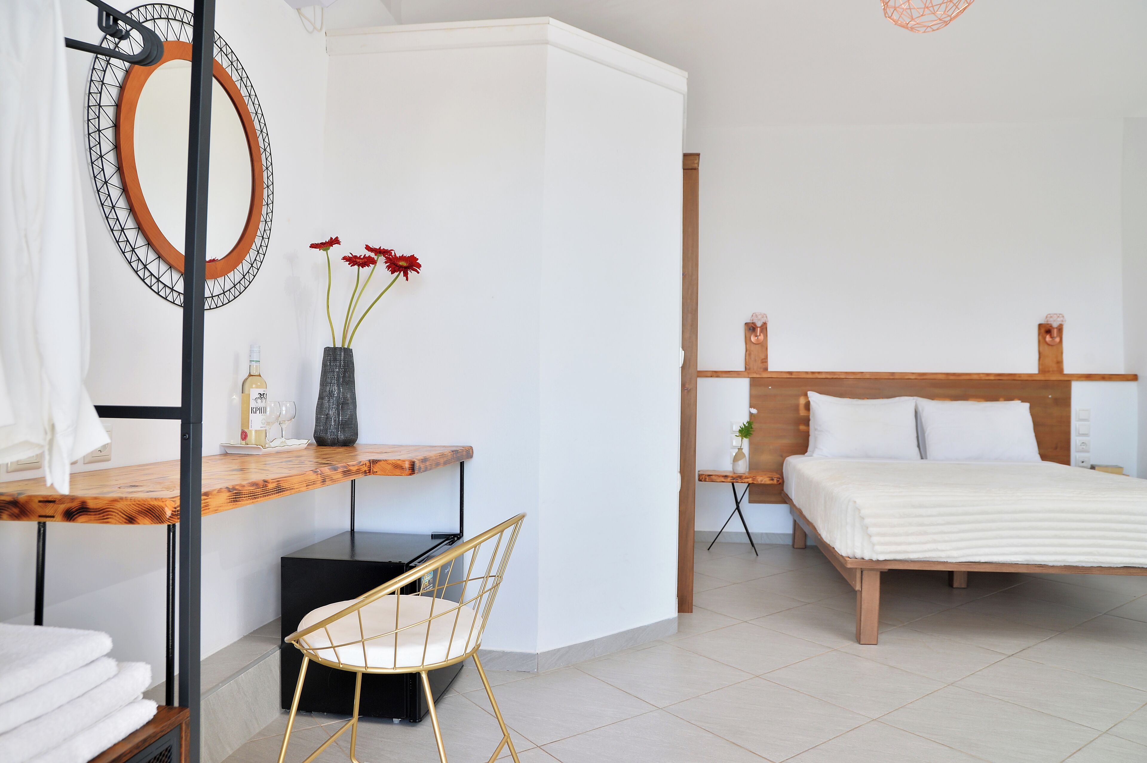 A bedroom with a wooden bed, a bedside table with a lamp, a chair, and a mirror on the wall.