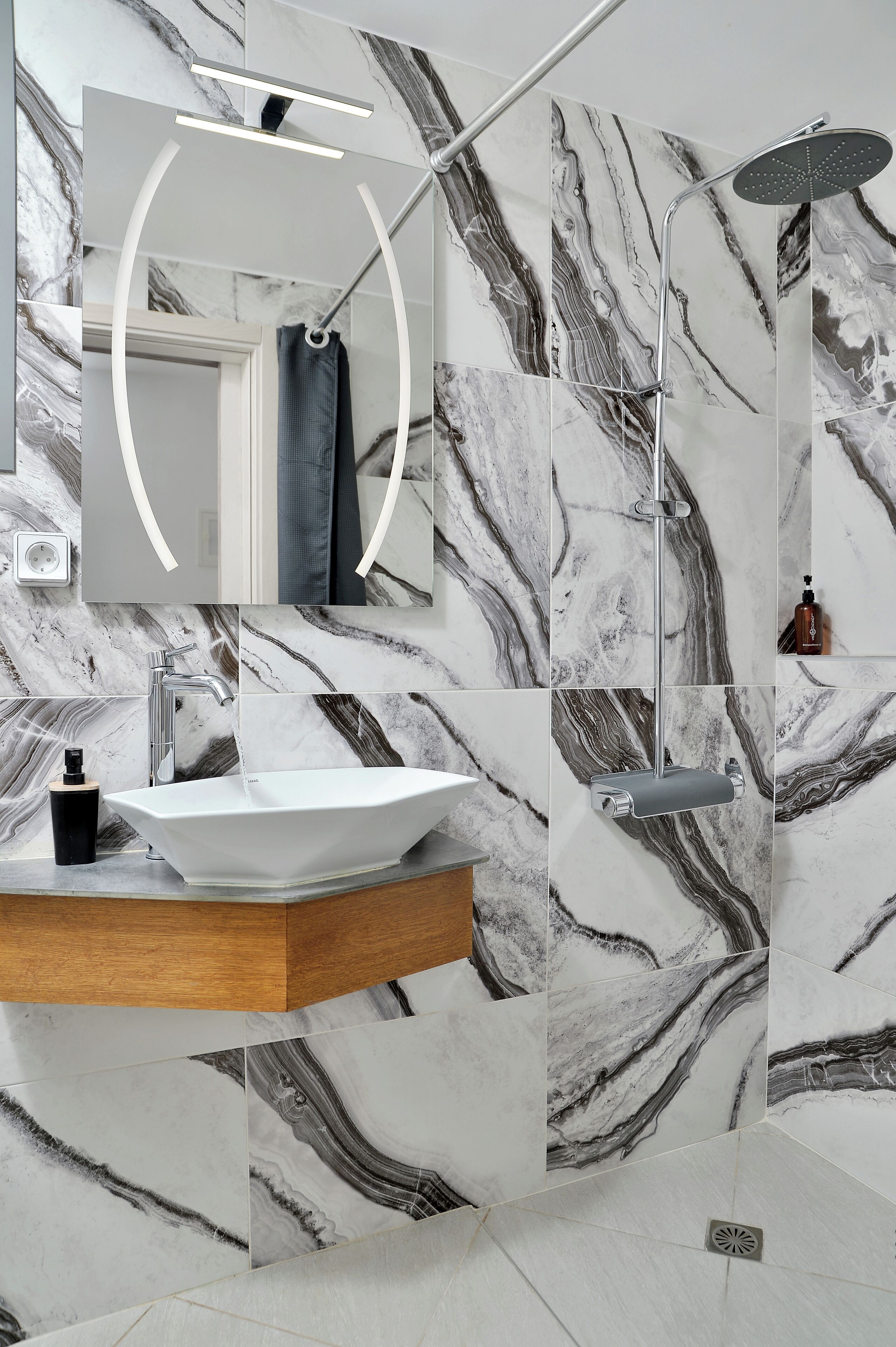 Une salle de bain avec un pare-baignoire en marbre, un lavabo sur pied, un miroir et une douche.