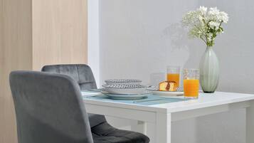 Uma mesa de jantar com um vaso de flores, pratos e copos de suco de laranja.