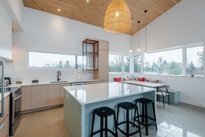 A modern kitchen with a large island, bar stools, and a dining area with a bench.