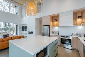 A modern kitchen with a large island, built-in appliances, and a dining area with a sofa.
