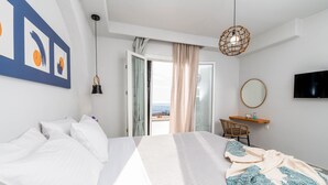 A bedroom with a bed, a desk, a chair, a TV, and a view of the outdoors. - Horizon Villa in Naxos Skyline (Naxos)