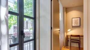 Ein Flur mit einem großen Fenster, einem Schreibtisch mit Stuhl und einem gerahmten Bild an der Wand.