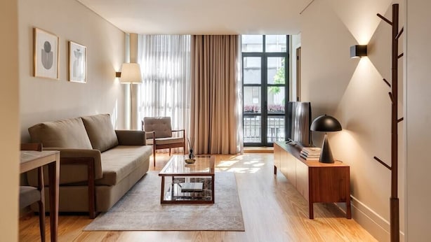 Ein modernes Wohnzimmer mit einer Couch, einem Sessel, einem Couchtisch und einem TV-Schrank.