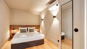 Ein modernes Schlafzimmer mit einem großen Bett, Nachttischlampen und einem Spiegel.
