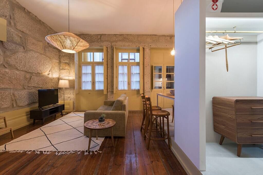 A living room with a stone wall, a sofa, a TV, a coffee table, and a hanging light fixture.