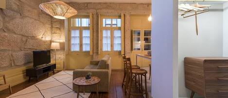A living room with a stone wall, a sofa, a TV, a coffee table, and a hanging light fixture.