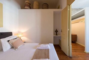 Une chambre Ă coucher comprenant un lit, une table de chevet, une lampe et donnant sur un placard et un escalier.
