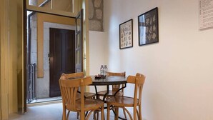 A dining area with a round table and four wooden chairs, a door, and two framed botanical prints on the wall. - Mercado Apartments #3T by DA'HOME (Porto)