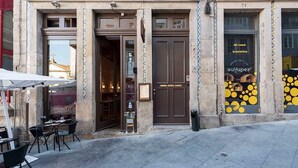 A building with a tiled facade, a central entrance with a door, and a window with a yellow and black design. - Mercado Apartments #3T by DA'HOME (Porto)