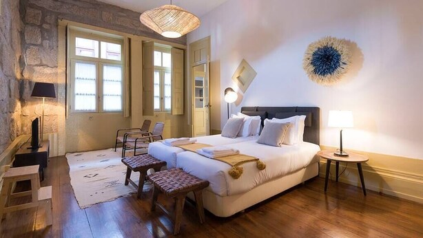 A bedroom with a bed, bedside tables, a chair, a small table, and a lamp. - Mercado Apartments #3T by DA'HOME (Porto)