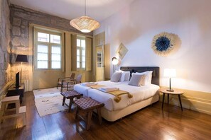 Une chambre à coucher avec un lit, des tables de chevet, une chaise, une petite table et une lampe.