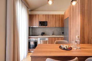 A modern kitchen with wooden cabinets, a microwave, oven, and a dining area with a wooden table.