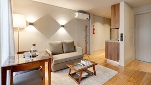 Un saló modern amb un sofà, una taula de centre, una taula de menjador i una zona de cuina.