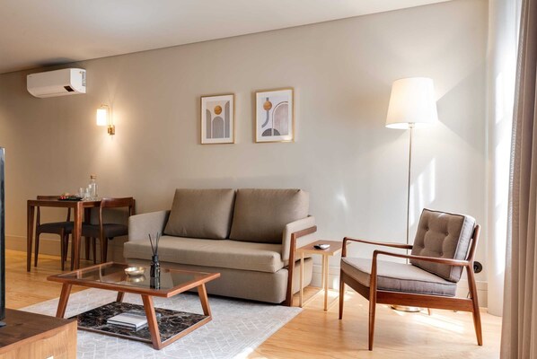 Una sala de estar moderna con sofá, sillón, mesa de centro y lámpara de pie.