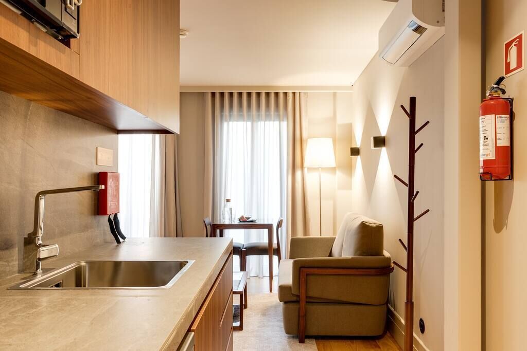 Ein modernes Hotelzimmer mit einer Küchenzeile, einem Essbereich und einer Sitzecke.