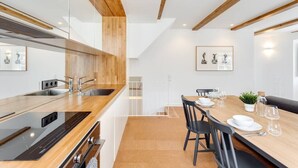 Una cucina moderna con elementi in legno, un'area pranzo con tavolo apparecchiato per due persone e opere d'arte alle pareti.