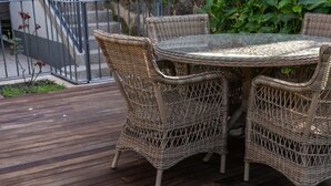 A wooden deck with wicker furniture and a glass table. - Porto Premium Villa S (Porto)