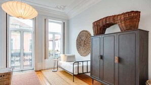 A room with a large window, a dark wooden cabinet, a wicker basket on top, and a woven wall decoration. - Porto Premium Villa S (Porto)