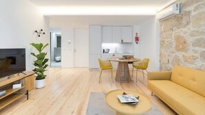 Una sala de estar moderna con televisor, sofá y comedor con sillas.