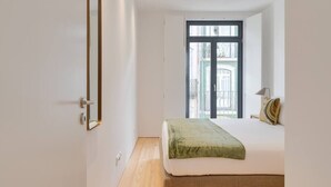 A bedroom with a bed, a window, and a door. - Alma da Casa by DA'Home #2E (Porto)