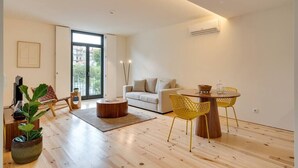 A modern living room with a sofa, a dining table with chairs, a coffee table, and a large window with a view of buildings. - Alma da Casa by DA'Home #3D (Porto)
