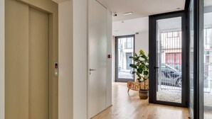 A hallway with a wooden floor, a white door, and a glass door leading outside. - Alma da Casa by DA'Home #3D (Porto)