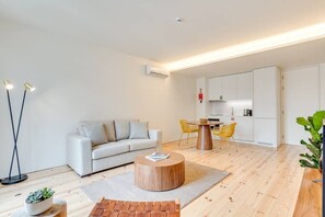 A modern living room with a sofa, round coffee table, and a dining area with chairs. - Alma da Casa by DA'Home #4D (Porto)