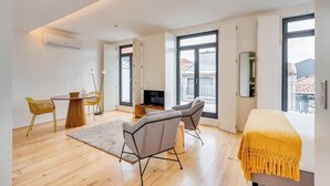 A modern room with a bed, a TV, a dining area, and large windows. - Alma da Casa by DA'Home #4E (Porto)