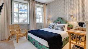 Ein Schlafzimmer mit Bett, Stuhl, Tisch und Fenster.