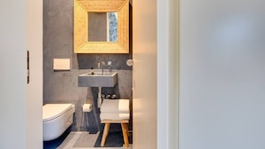 Ein modernes Badezimmer mit integriertem Waschbecken, Toilette und Spiegel mit geometrischem Rahmen.
