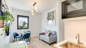 Ett kompakt bostadsutrymme med en matplats, ett litet kök och en soffa.