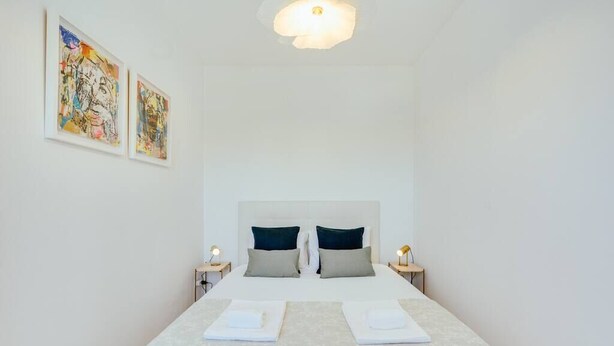 Ett hotellrum med en stor säng, två sängbord och två tavlor som hänger på väggen.