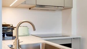 Ett modernt kök med en diskho i rostfritt stål, en inbyggd ugn och en bänkskiva i ljus färg.