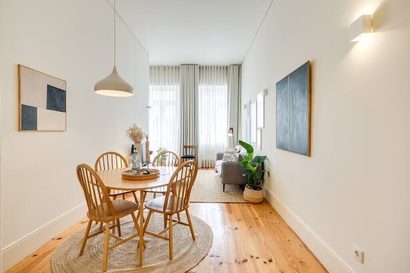 Un coin repas avec une table ronde en bois, quatre chaises et un tapis tissé.