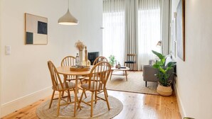 Ein modernes Wohnzimmer mit einem runden Holztisch, einer Couch und einer Topfpflanze.