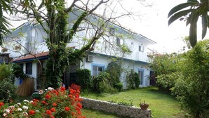 Un edificio bianco con decorazioni blu, circondato da un giardino curato con fiori rossi e bianchi.