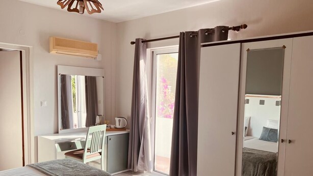 Una camera da letto con un letto, una scrivania, una sedia, un armadio e una porta scorrevole su un balcone.