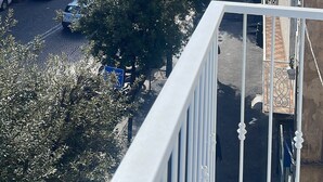 A view from a balcony overlooking a street with parked cars and buildings, including a large building under construction. - Quadruple Room. Berenice Suites (Napoli)