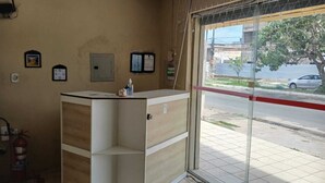 A reception area with a counter, a fire extinguisher, and a window with a view of the street. - Hostel Mar (São Luís)