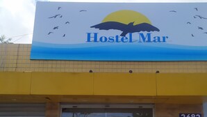 A Hostel Mar sign with a bird silhouette and a sun, number 2682, and a closed shutter door. - Hostel Mar (São Luís)