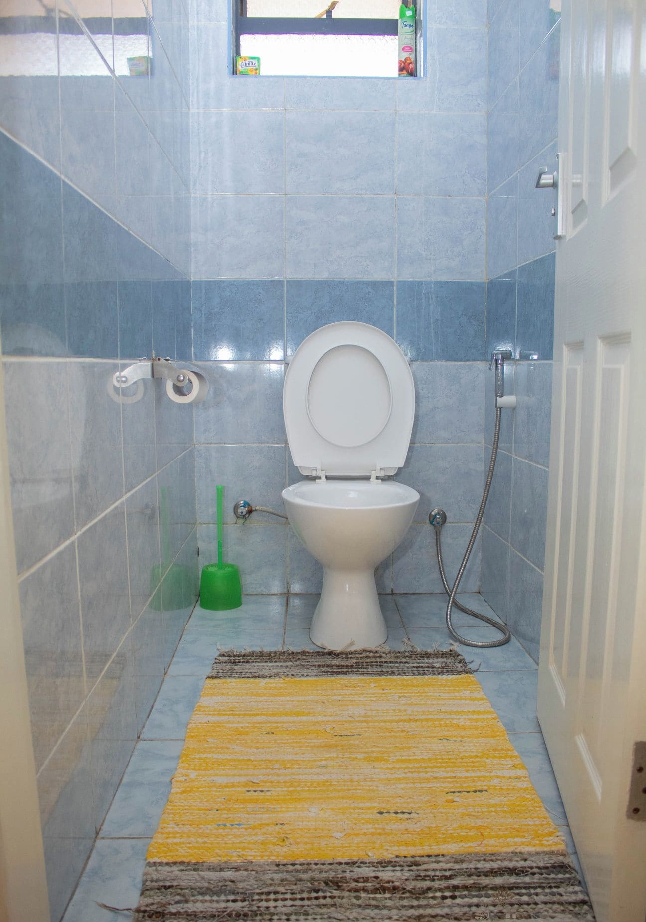 A small bathroom with a toilet, a shower, and a window.