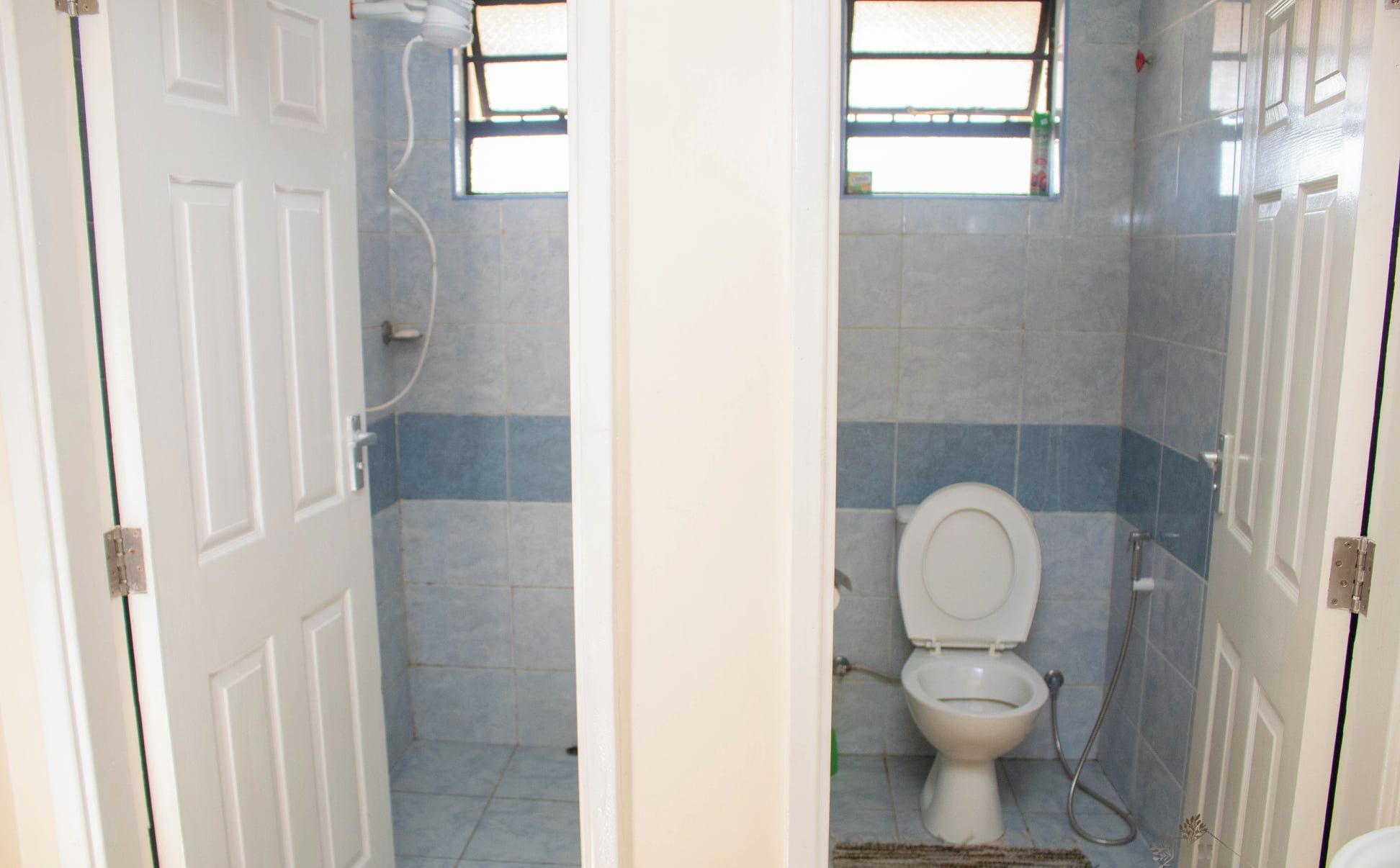 A small bathroom with a toilet, a shower, and a window.