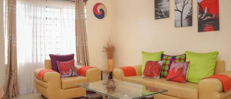 A living room with two beige sofas, a glass coffee table, and a red and yellow striped rug.