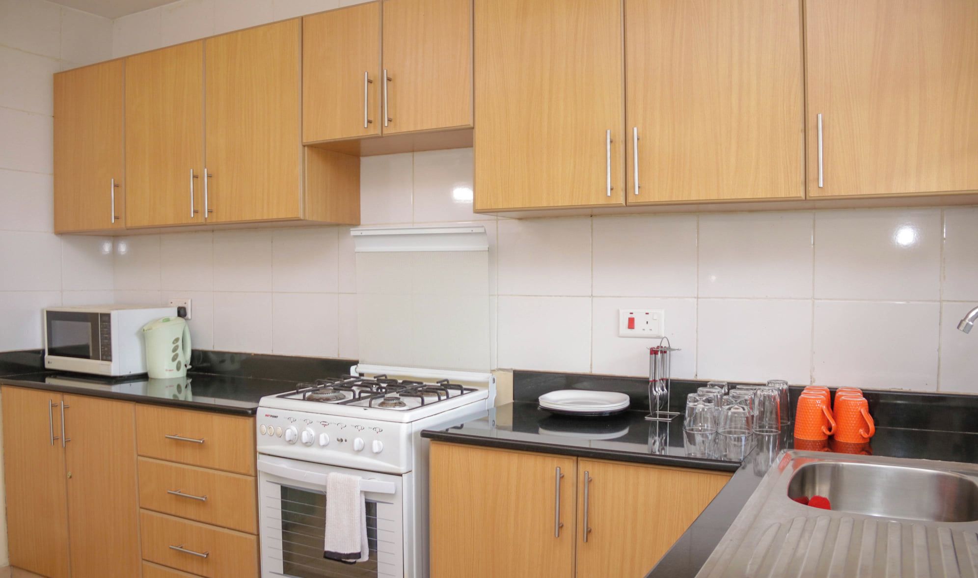 Una cocina con armarios de madera, estufa, microondas y un fregadero.