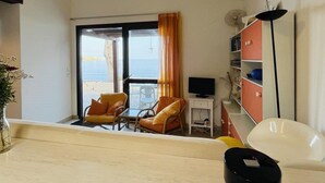 A room with a balcony, a TV, a bookshelf, and a chair. - 3-Room Apartment for 6, Steps from Beach, Terrace, Parking Included (Lumio)