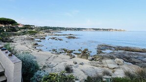 A coastal landscape with rocky shores, a clear sky, and distant buildings. - 3-Room Apartment for 6, Steps from Beach, Terrace, Parking Included (Lumio)
