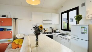 A modern kitchen with white cabinets, a long countertop, and a window. - 3-Room Apartment for 6, Steps from Beach, Terrace, Parking Included (Lumio)